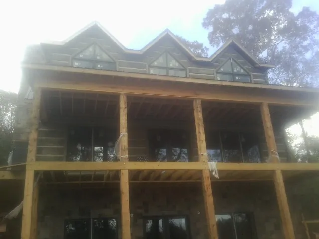 Dormers and porch framing on a large log home under construction — Roof Coating work by our crew in Gold Hill